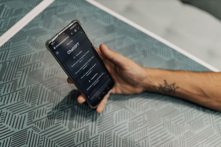 A hand holding a phone with an AI assistant conversation open on screen.