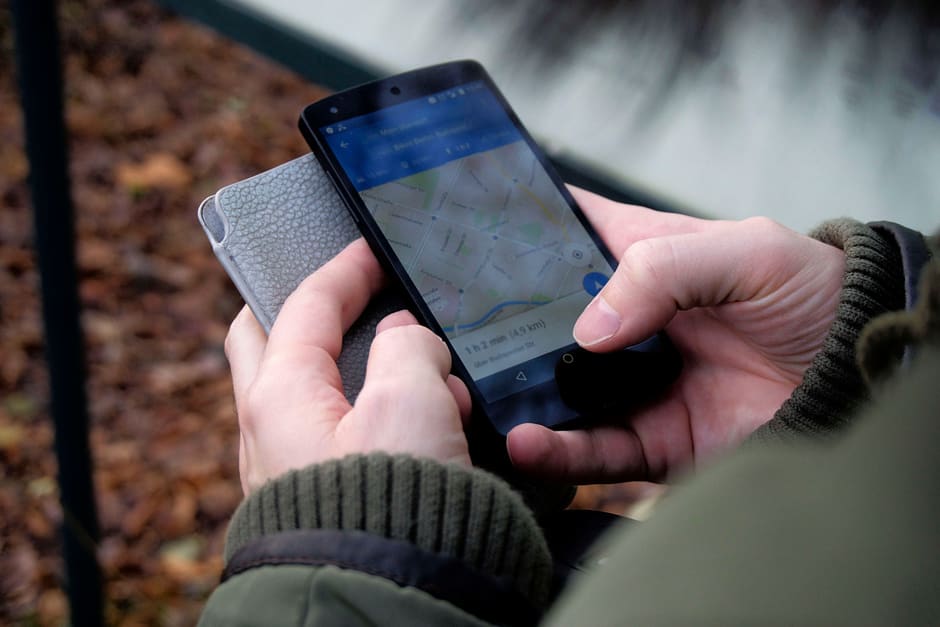 Someone outdoors in a winter coat holding a phone with Google Maps open.