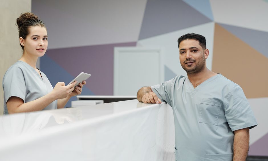 Two members of a practice team at a reception desk, one holding a phone.