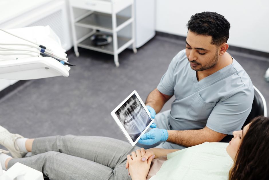 A dentist showing a dental x-ray on a tablet to a patient in the chair.