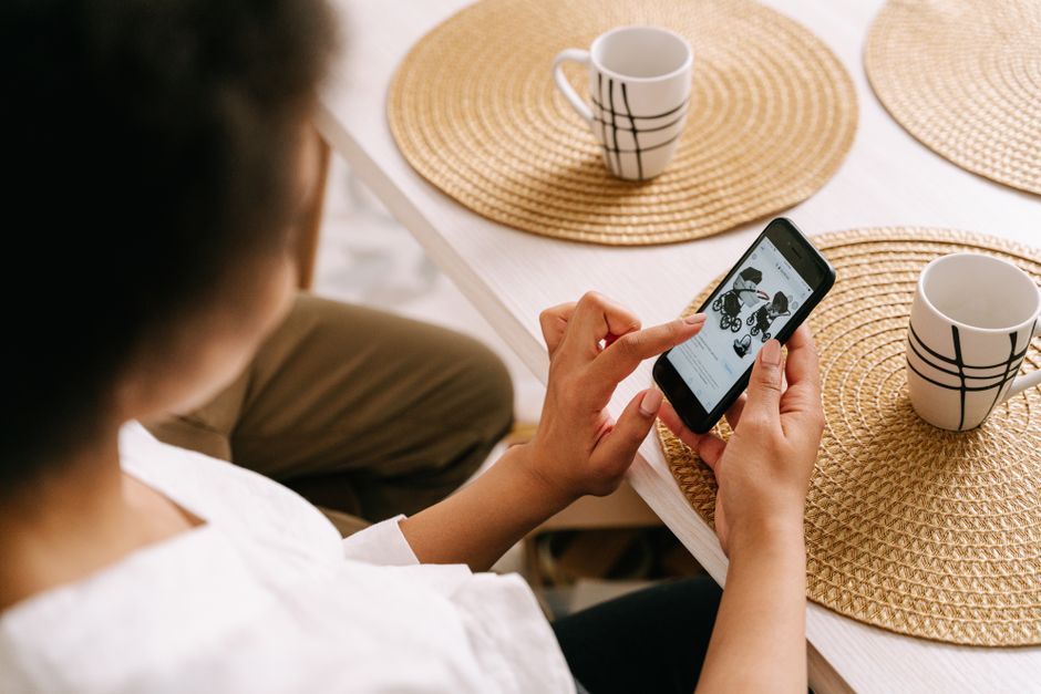 Someone looking at a phone at a kitchen table.