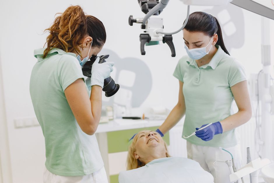 Two clinicians working together over a patient in a bright treatment room.